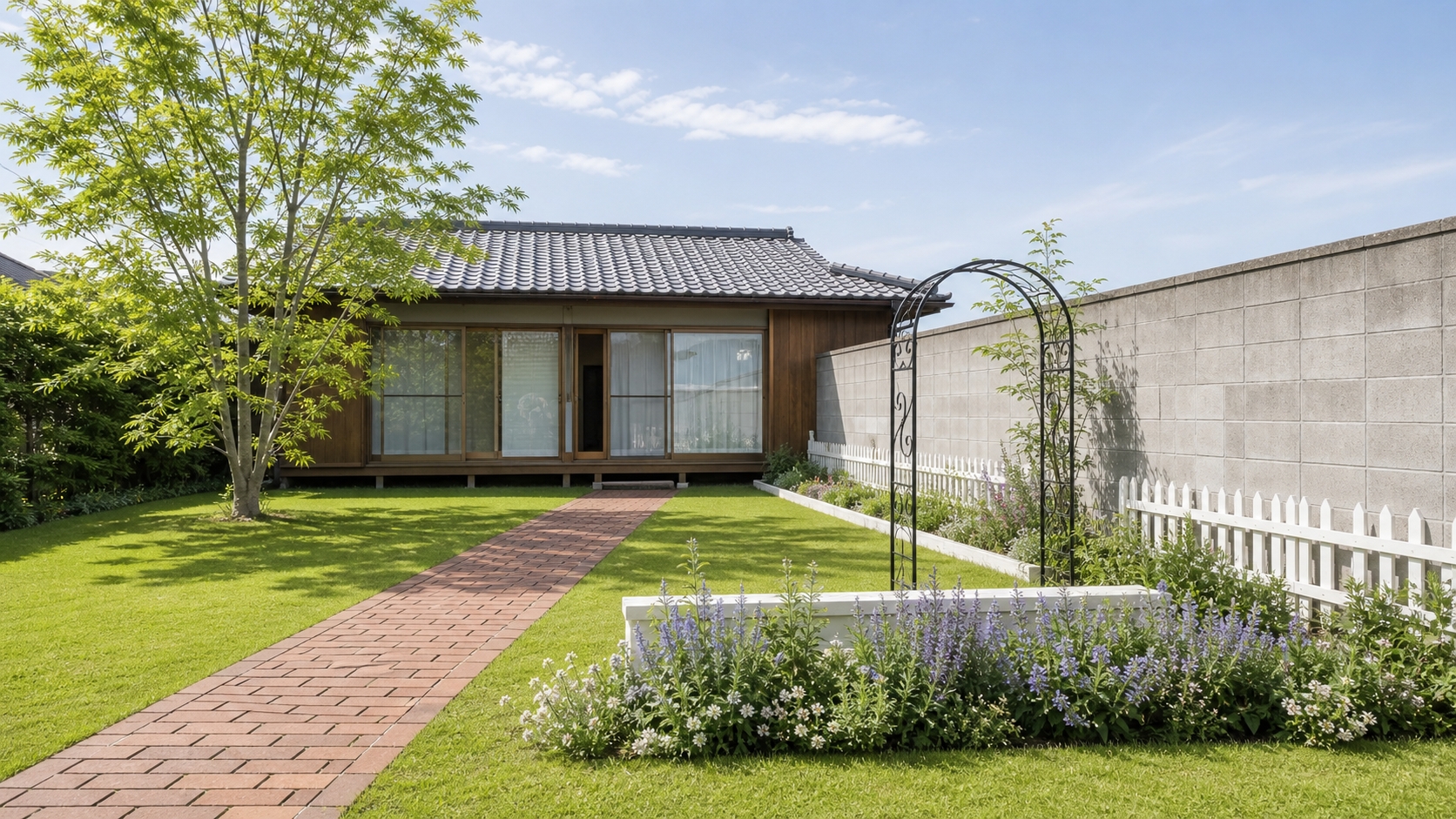 同じ敷地を洋風に仕上げた庭。芝生、レンガの小道、白いフェンス、宿根草の花壇